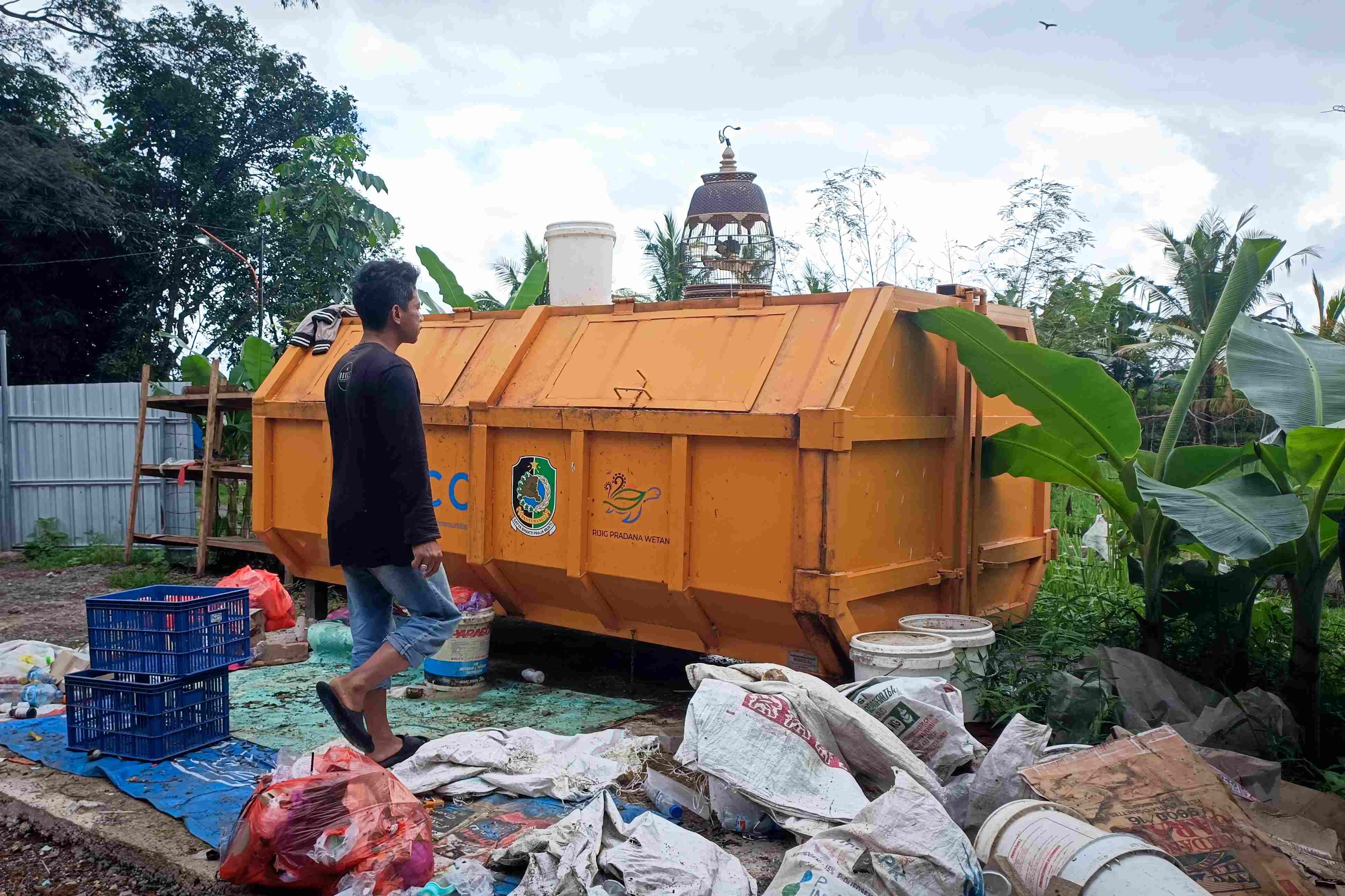 Petugas pengelola sampah melihat kondisi bak penampungan yang sudah penuh di Dusun Jalen, Desa Setail, Genteng, Banyuwangi, Jumat (1/8/2025).